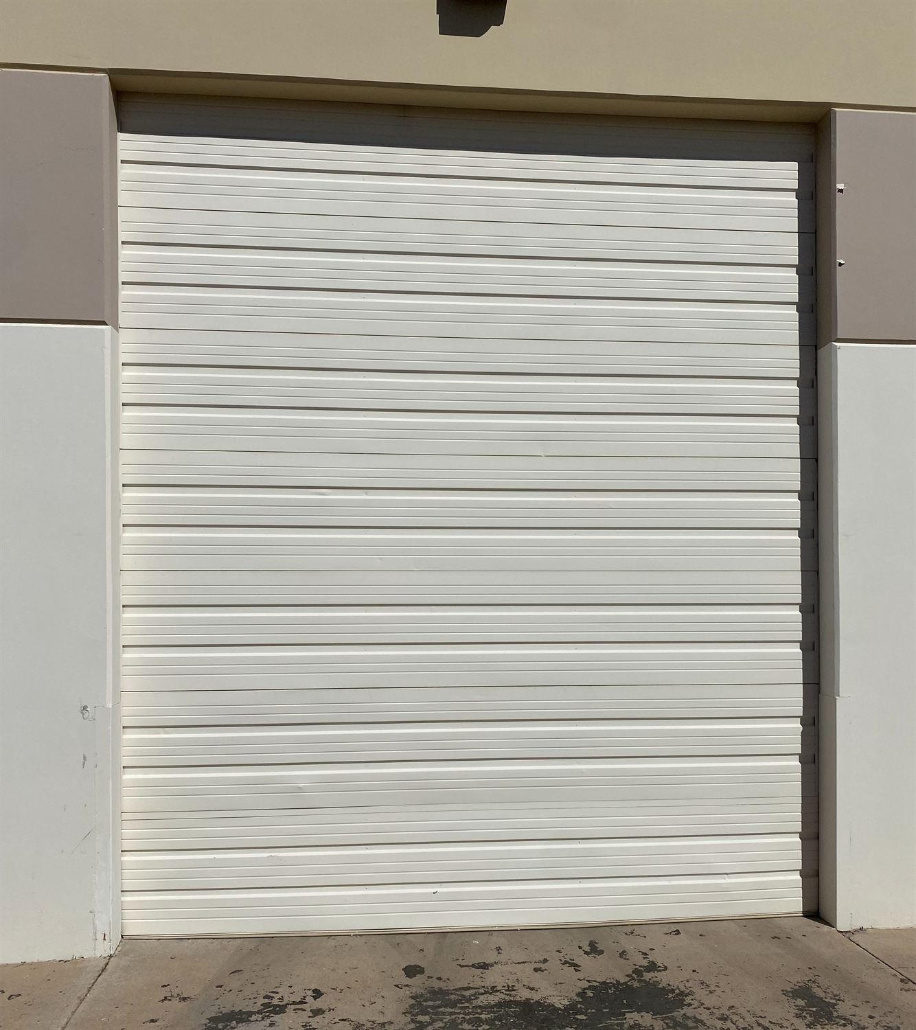 Newly installed white commercial sectional garage door, exterior view